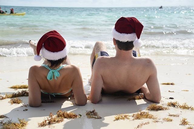 couple wearing Santa hats on the beach