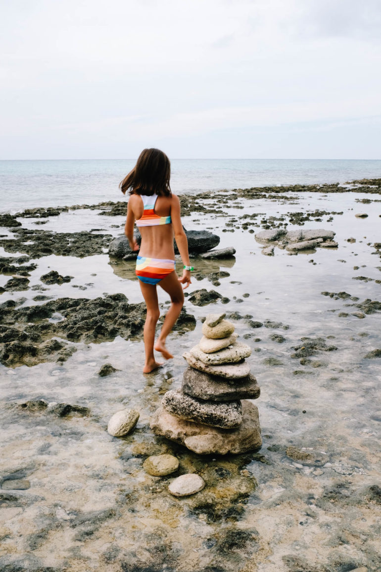 daughter walking on rocky beach near small rock structure